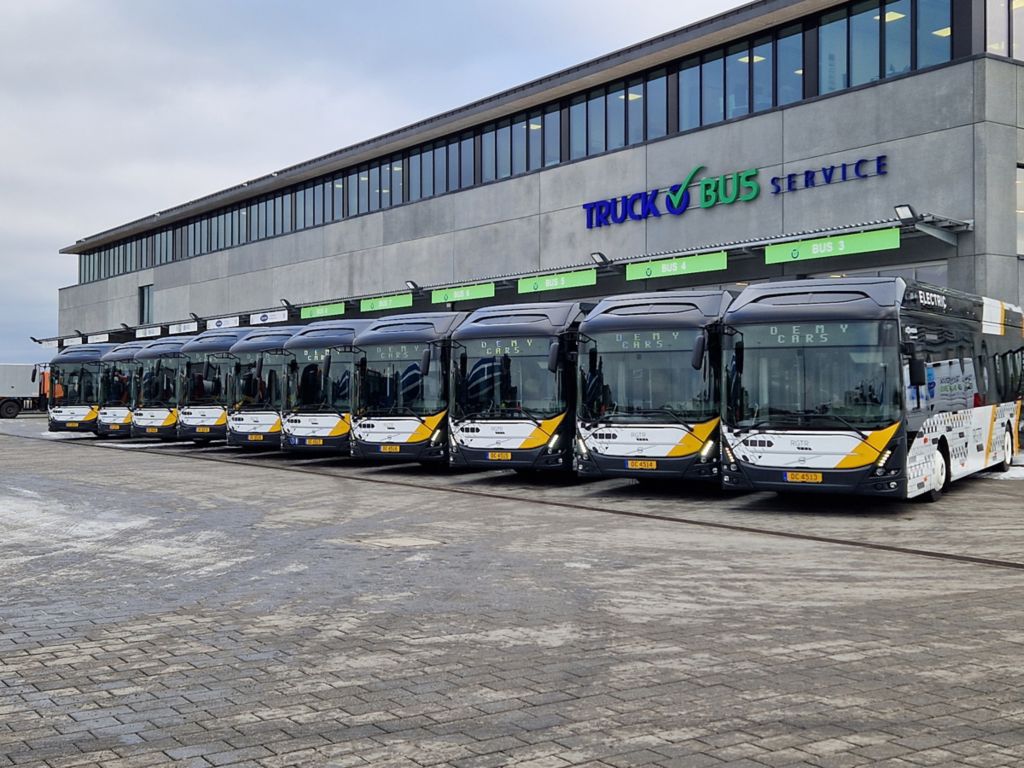 Tio elektriska Volvobussar parkerade framför ett garage.