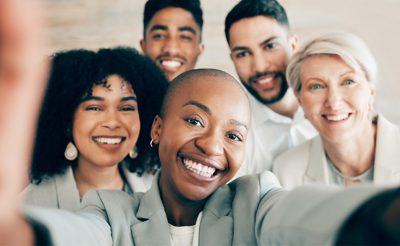 Selfie, business and smile for company diversity, team collaboration and professional happiness in workplace. Group, people and portrait for about us web post on social media, website or black woman.