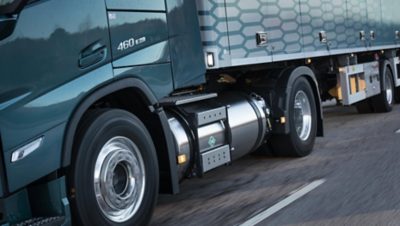 Close-up of a Volvo truck driving on the road, showing the fuel tank and wheels in motion.