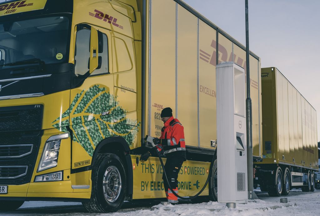 Person plugging in charger to charge an electric DHL Volvo Truck