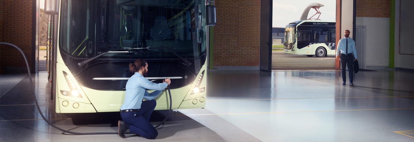 Un autobús en el depósito. Un conductor se dispone a cargar las baterías del autobús.