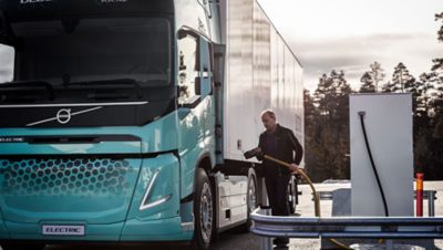  A man about to insert a charging cable into a Volvo FH Electric Truck.
