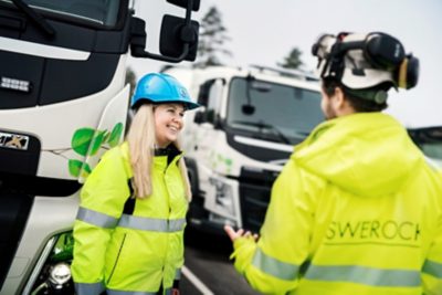 Construction site workerswith Volvo Electric trucks in background