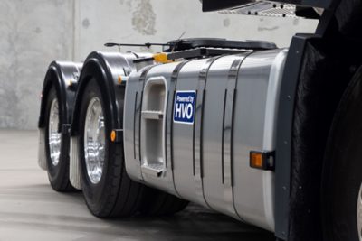 Close-up of a Volvo truck driving on the road, showing the fuel tank and wheels in motion.