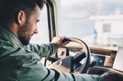 Un conducteur et son chien marchent devant un véhicule Volvo garé dans une station-service