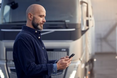 Driver with phone in front of truck                        