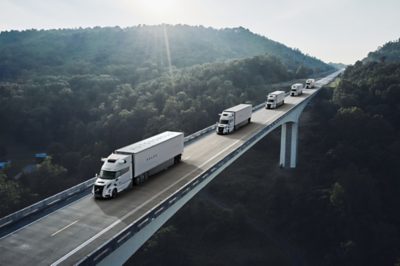 A line of autonomous trucks on a bridge driving on a sunny day