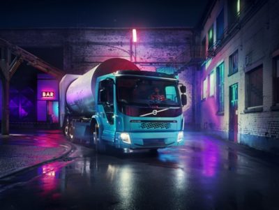 Refuse truck in a bar district backyard, close-up, angle: passenger s side visible. The Volvo FE Electric is available with a low-entry cab for convenient entry and exit and to give the driver an excellent visibility of surrounding traffic and vulnerable road users.