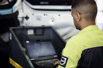 Un técnico de servicio de Volvo sostiene una computadora junto a un camión