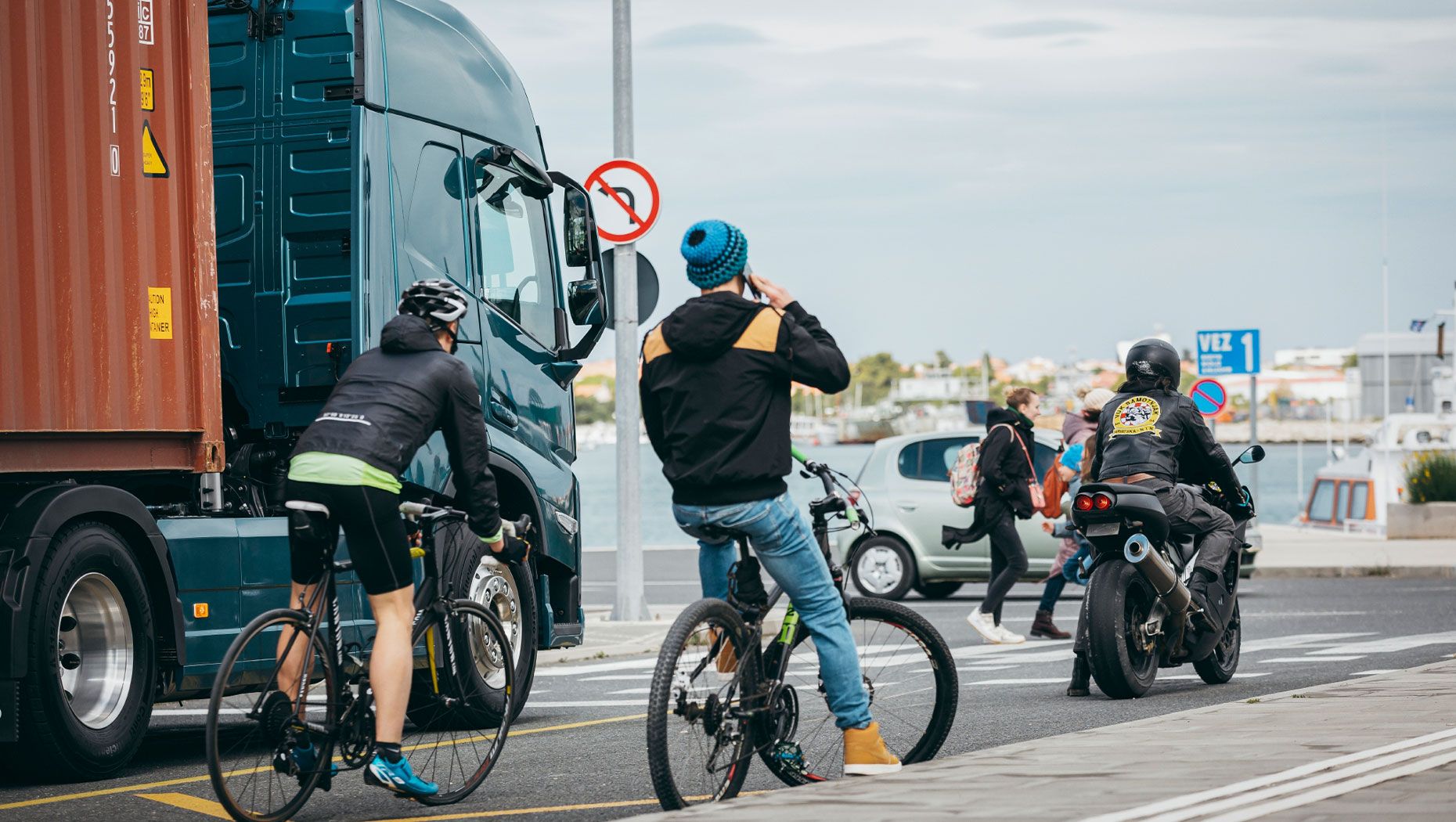 Dviratininkai, pėstieji ir mopedų vairuotojai laukia žalios šviesoforo šviesos didmiesčio sankryžoje