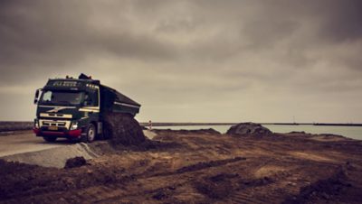 Földet szállító Volvo teherautó üríti rakományát.