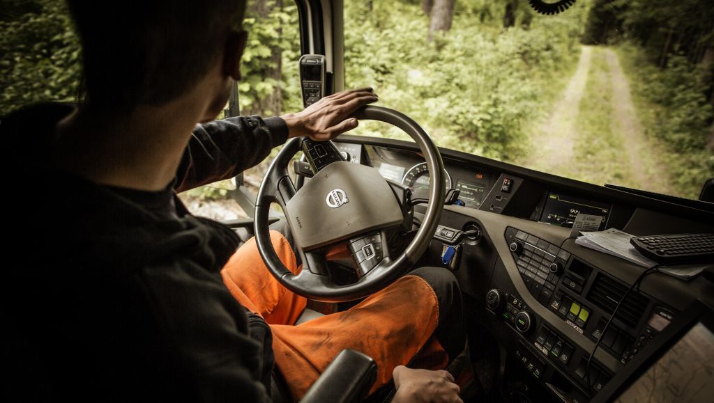 Șofer manevrându-și autocamionul în pădure.