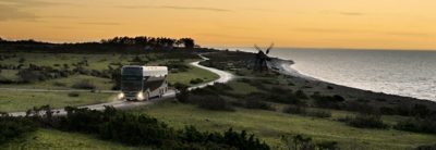 Autobus à étage sur une route de campagne avec la mer en arrière-plan