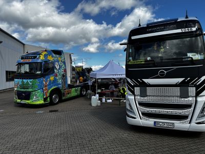Die farbenfroh gestaltete Sattelzugmaschine aus dem Volvo Trucks Malwettbewerb 2025 sowie ein Volvo FH der CM Logistik Gruppe als Kindertaxi.