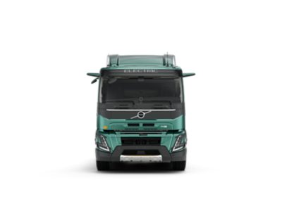 Студийная фотография грузового автомобиля Volvo FMX Electric (вид спереди). На фото видна бирюзовая кабина, аэродинамическая решетка и маркировка «ELECTRIC» над лобовым стеклом.