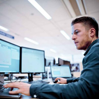 A man sits in front of three screens in the Volvo Trucks International Uptime Center