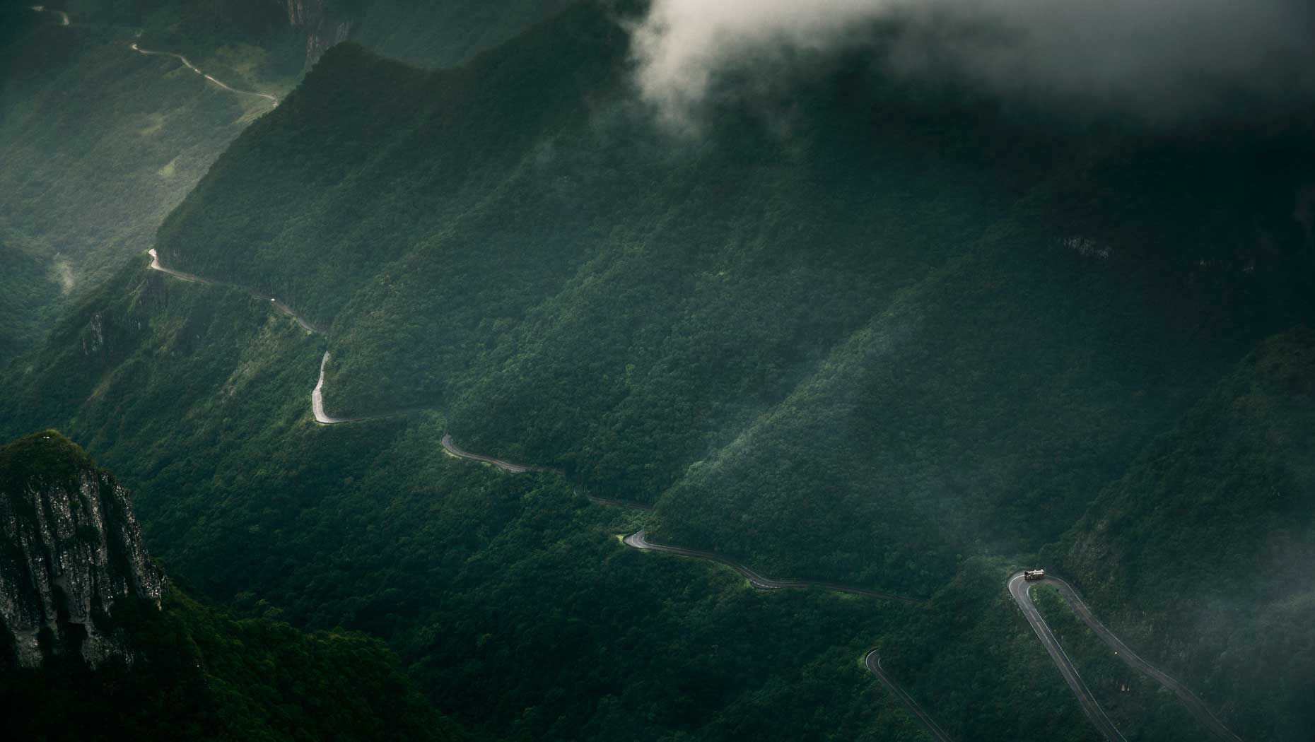 Un camión avanza por una carretera que atraviesa las altas montañas