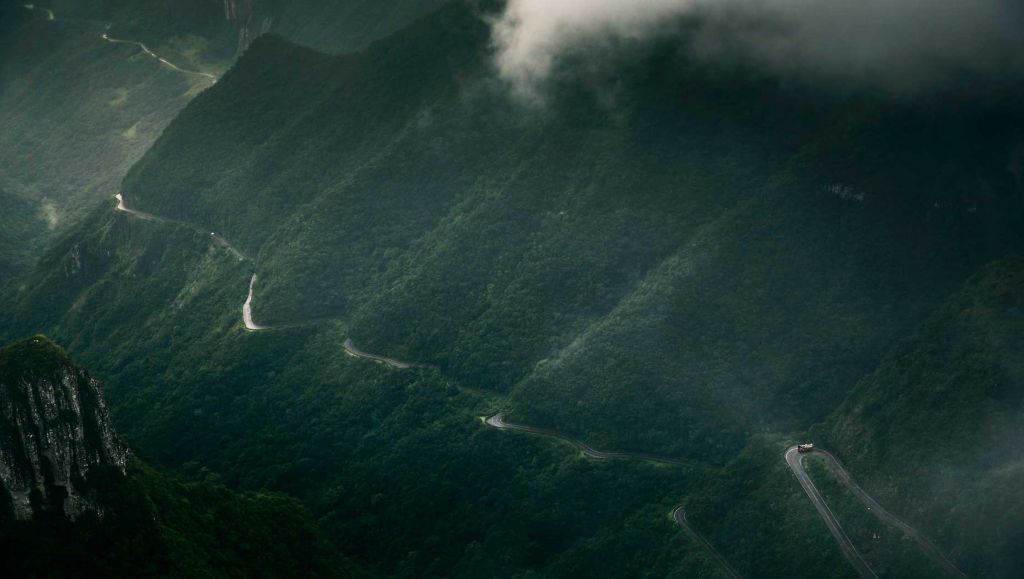 A truck journeys along a road that cuts through high mountains