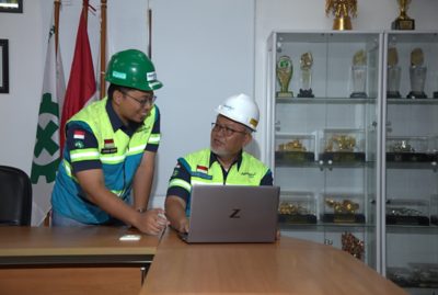 Two workers in safety gear collaborate in an office setting.