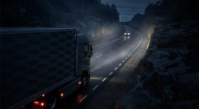  Self driving Volvo truck driving on a road at night, meeting a Volvo car in the opposite car lane.