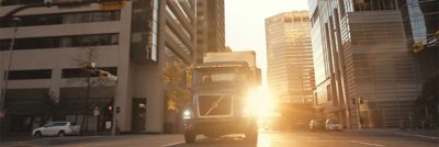 Volvo Autonomous truck running through an empty city with the sun rising in the background.