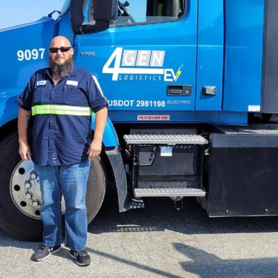 Henry Perea egy kék Volvo teherautó előtt áll