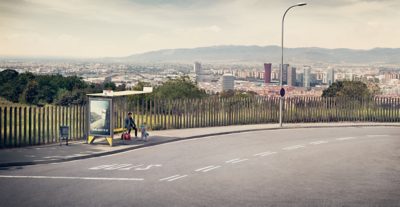 A man and a girl are waiting at a bus stop in the remote parts of a big city