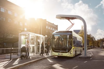 Bild som visar en Volvo Electric-buss som laddas via en OppCharge-pantograf på en busshållplats.
