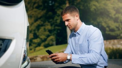 A driver with a smartphone doing a vehicle checkup using the Daily Inspection service 