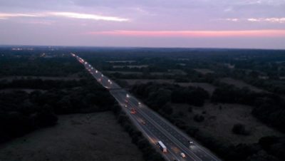 Aerial shot of highway with many cars and trucks driving in the evening