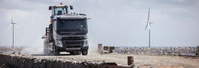 Водитель в каске сидит в кабине с открытой дверью