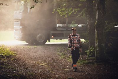 A truck parked behind a man walking through a forest