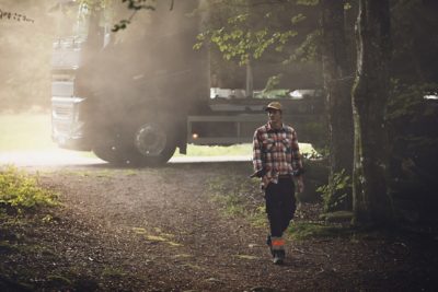 A truck parked behind a man walking through a forest
