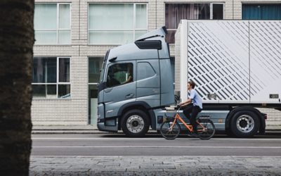 Cyclist rides by Volvo FM in the city