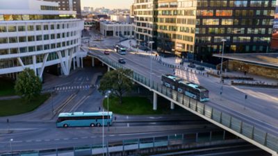 A grade-separated intersection with an articulated electric city bus above and an electric coach below