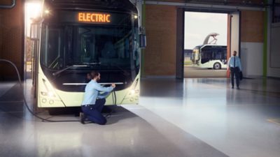 A driver plugging the charging cable into the charging inlet  on a Volvo electric city bus 