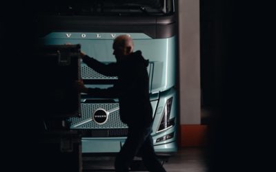 Un bărbat stă în picioare în fața unui camion Volvo FH