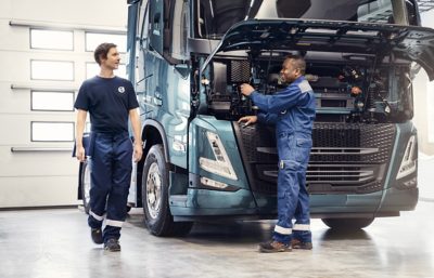 Two technicians speak in front of truck in the workshop