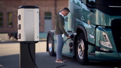 A man inserting the charging cable from a Volvo Energy charging pole into his electric truck.