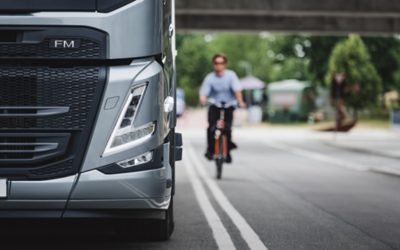 Volvo FM circulând pe șosea și o persoană pe bicicletă în spate