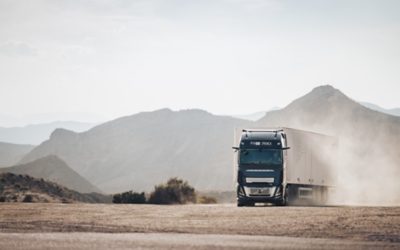 De Volvo FH16 rijdend op een stoffige weg met bergen op achtergrond
