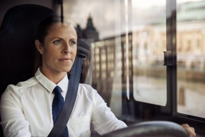 A female bus driver with a firm focus on the road ahead.