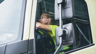 Female truck driver sitting in a truck and looking out