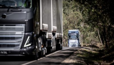 Truck driving on road with mountains on the side, and road signs 