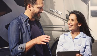 Man and woman posing for a candid photo in front of a truck 