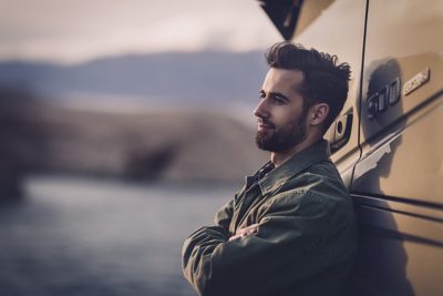 A man leans against the cab of his truck