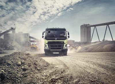 A Volvo FMX drives offroad through an industrial site