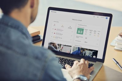 A fleet manager using the Volvo Connect dashboard on a laptop to monitor vehicle status and fuel efficiency scores, helping predict uptime, reduce unplanned stops, and run daily operations more smoothly.