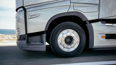 A close-up of a truck's front wheel on the highway