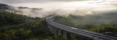 Ein Lkw fährt über eine Brücke hoch über den Baumwipfeln